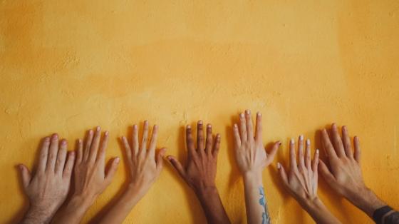 Diverse hands on a yellow wall